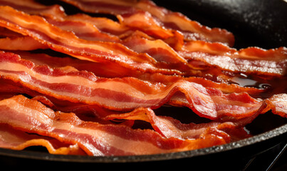 Rashers of bacon crisping up in a frying pan, creating a tempting and delicious scene.