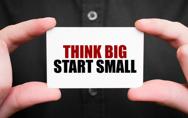 Businessman holding a card with text THINK BIG START SMALL, business concept