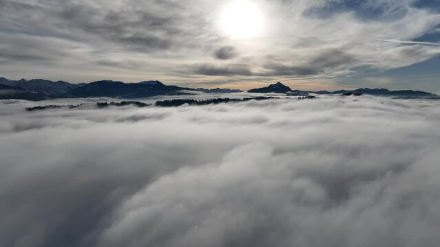 Drohnenvideo im Winter mit Nebel im Tal und Sonne im Gebirge