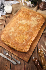 closed square pie with braided patterns on a wooden background