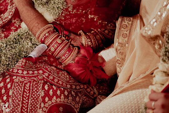 ndian bride and groom during Gath Bandhan ritual ceremony....pheras ceremony....Closeup of indian wedding couple holding hands