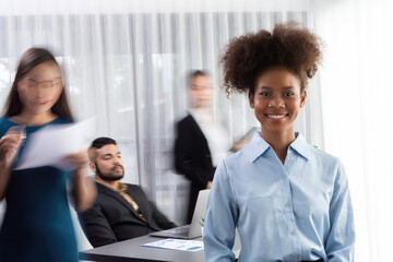 Young African businesswoman portrait poses confidently with diverse coworkers in busy meeting room...