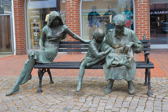 Germany, Lower Saxony, Rotenburg an der Wümme - July 27, 2023: The bronze sculpture Drei Generationen depicts a child with grandmother and mother on a bench.