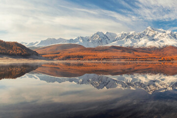 Fototapeta na wymiar Reflection of snowy peaks on the surface of a mountain lake.