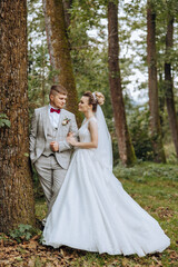 lovely and stylish newlyweds are hugging and smiling against the background of autumn nature in a beautiful garden. An incredibly beautiful young bride leaned against the shoulder of her beloved groom