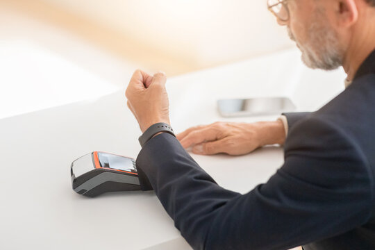 A sophisticated man in a business suit completes a purchase using a contactless smartwatch