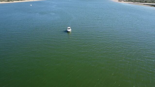 Aerial drone view of a motor boat moored in the Piedras river and fishing, Between the El Portil beach village and La Flecha sand bank