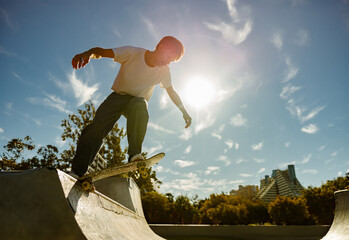 Active skateboarder jumping and performing a trick in a ramp of a skate park © Kostiantyn