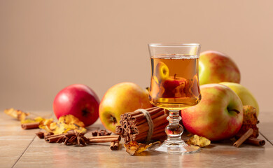 Apple juice with apples, cinnamon, and anise on a beige background.