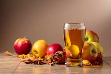 Apple juice with apples, cinnamon, and anise on a beige background.