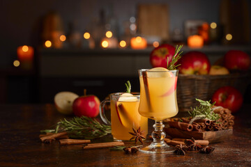 Mulled cider with apples, cinnamon, rosemary, and anise on a background of burning candles.