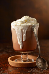 Hot chocolate with whipped cream in a glass mug.