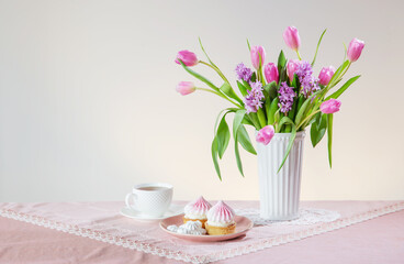 cup of tea and cupcakes with spring flowers in light colors