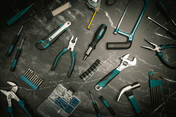 Assorted Hand Tools Laid Out on black marble background, top view with space for text