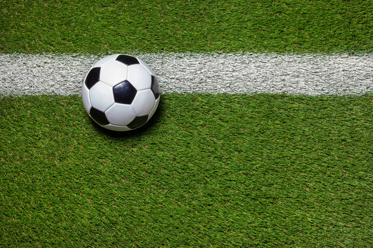 Soccer ball on grass field with stripe overhead view