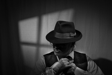Film Noir style detective wearing a Fedora hat, tie and waistcoat in a dark, seedy office with a...