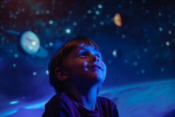 A satisfied boy in the planetarium looks with delight at the projection of space, stars and planets - obrazy, fototapety, plakaty