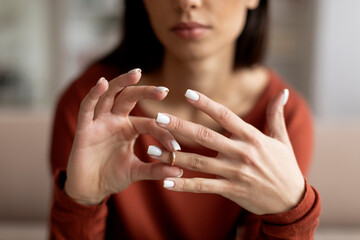 Closeup shot of upset young woman taking off wedding ring at home