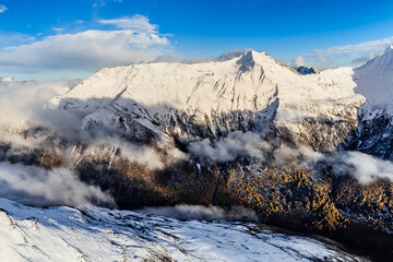 Bird's eye view from drone of snow mountain ridge and peak with cloud at sunset time at Dafeng base camp on the Siguniang Shan mountain in Changping Gou National Parks ,Rilong,Chengdu, China