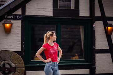 Pensive woman standing by a timber-framed house on Worth Street