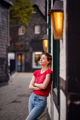 Woman leaning against a traditional black and white timbered house