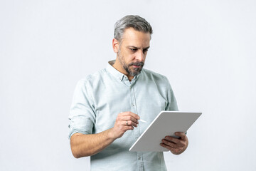 Bearded man holding and looking at tablet computer for online work isolated on white.
