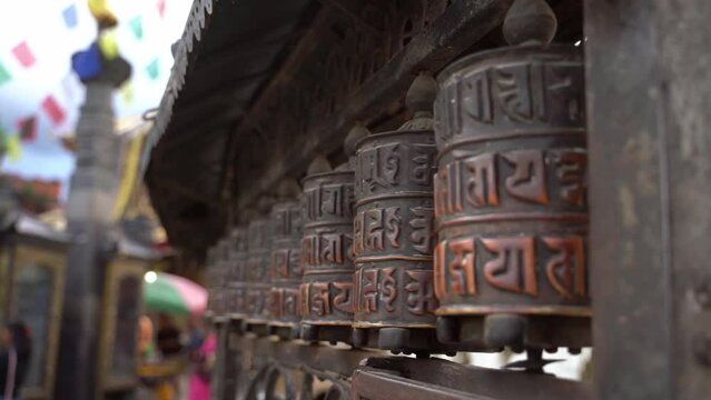 Spinning religious prayer wheels with written mantra Om Mani Padme Hum. Kathmandu, Nepal.
