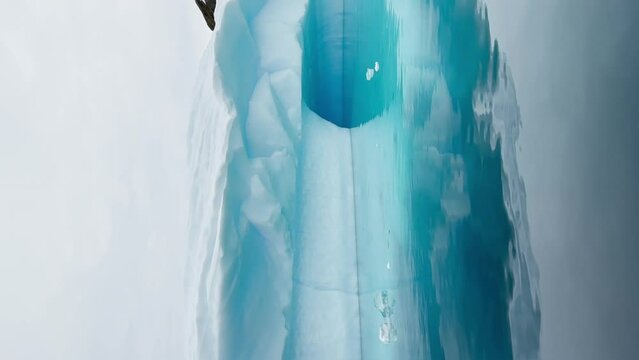 A huge high breakaway glacier is passing by in the southern ocean off the coast of Antarctica, the Antarctic Peninsula, the Southern Circle, azure water, cloudy weather