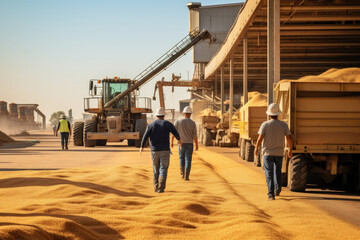 Workers stride across the granary yard, where heaps of golden grain form a carpet under the harsh sunlight, with machinery and silos in the backdrop - obrazy, fototapety, plakaty