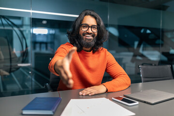 Friendly bearded young indian businessman outstretching hand