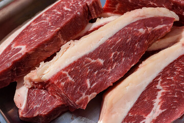Barbecue picanha meat, raw and sliced ​​close-up.