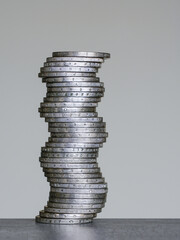 Unstable coins stack of two euro coins on a grey background, future balance concept