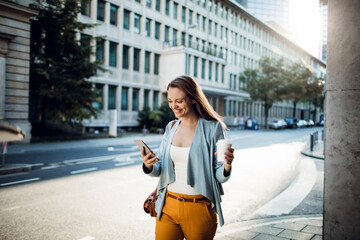 Fototapeta premium Young adult woman using her smart phone while commuting in the city