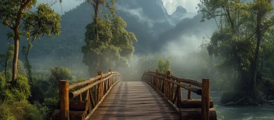 Selbstklebende Fototapete Waldfluss Scenic wooden bridge crossing tranquil river in lush green forest landscape