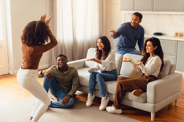 Diverse group of friends engages in game of charades indoors