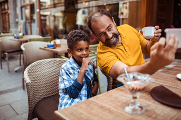 Stepfather taking selfie with child son at city cafe