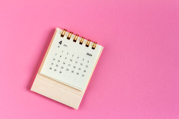 Desk calendar for April 2024 on a pink background.