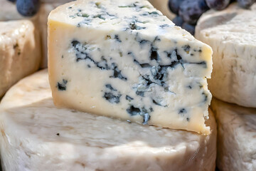 Fototapeta na wymiar Roquefort A close-up image of a wedge of blue cheese, showing its distinctive blue-green veins and crumbly texture.