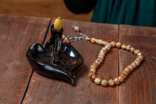 On the table there are steaming incense trailing smoke and rosary fasting Ramadan