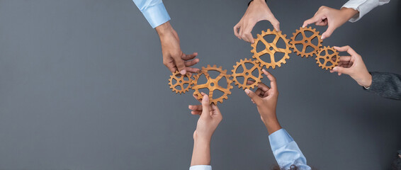 Panoramic shot top view of business people holding cog wheel as unity and teamwork in corporate...