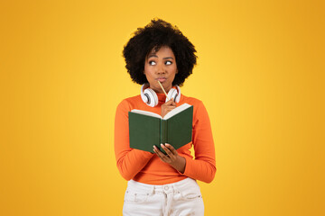 Contemplative young African American woman with afro hair, wearing headphones