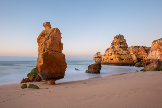 Long exposure image of the rocky Algarve cliff coast in south Portugal at sunset.
