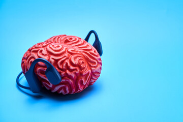 Red rubber brain with headphones on a blue surface. Brain rest concept.