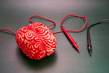 Red human brain next to red and black wires of a medical machine.