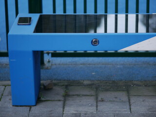 Mobile phone is charged using wireless charger on street bench. Solar battery