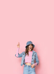 Beautiful girl in a denim hat and jacket on a pink background.