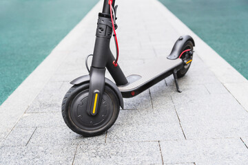 Close up photo of electric scooter standing on the concrete pavement. Green ecologically sound...