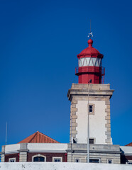 Fototapeta na wymiar The red tower of the lighthouse against the bright blue sky, low angle view.