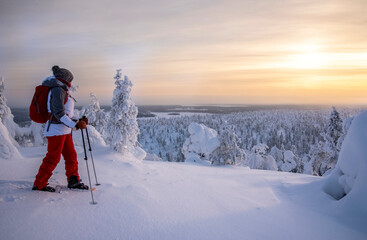 Woman snowshoeing in sunset in Lapland Finland