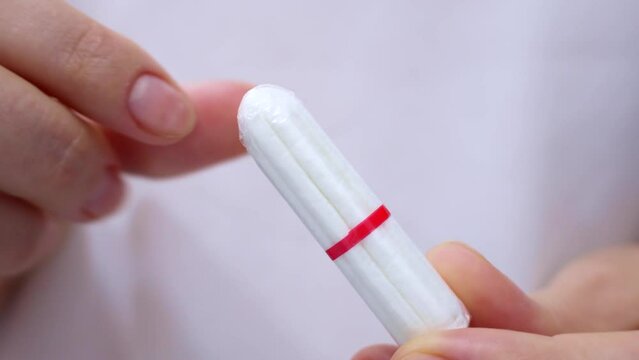 Woman hands holding white cotton sanitary tampon for monthly period close up